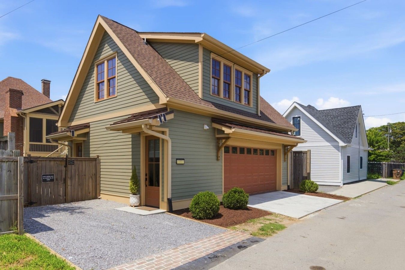 Une maison à deux étages avec un garage, un porche à l’avant et une allée.