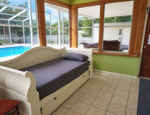 Quarto com cama, janela e vista para uma piscina.