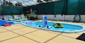 Piscina com brinquedos infláveis, espreguiçadeiras e área coberta com lona verde.