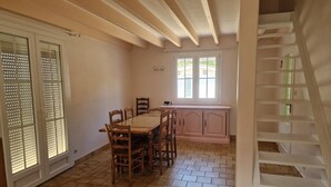 A dining area with a wooden table and chairs, a kitchen with a pink cabinet, and a staircase. - Grande maison pour toute la famille avec de l espace et un étang (Reignac)
