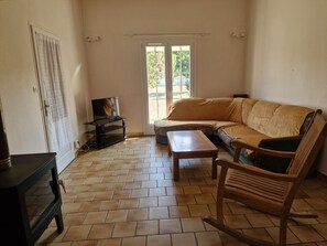 A living room with a sofa, a wooden table, a television on a stand, and a door with a curtain.