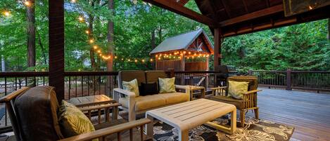 Une terrasse extérieure avec des meubles en bois, des guirlandes lumineuses et un espace abrité doté d’un toit en métal.