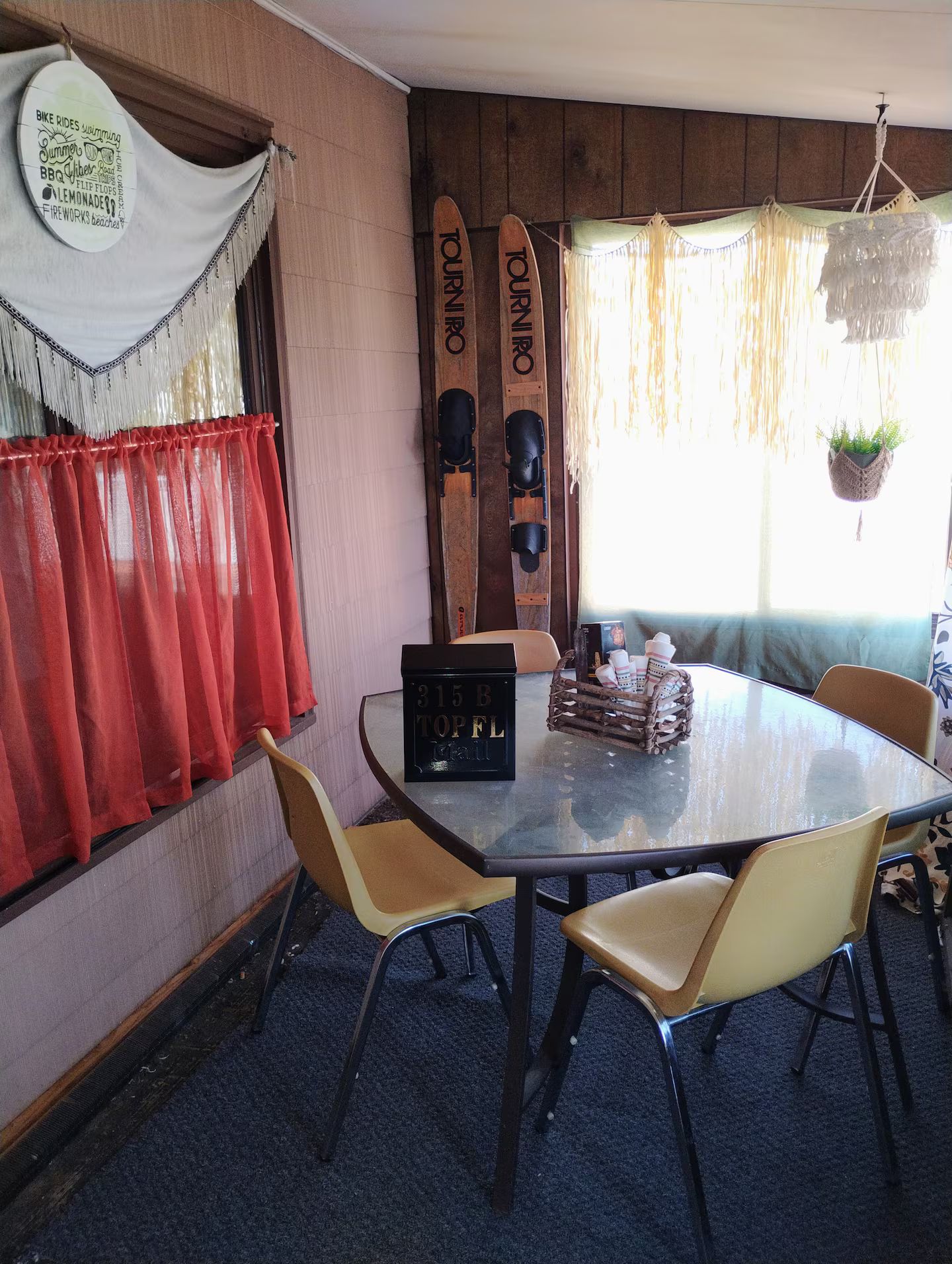 Un coin repas avec une table ronde, quatre chaises, un juke-box et des planches de surf en bois accrochées au mur.