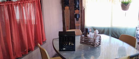 Un coin repas avec une table ronde, quatre chaises, un juke-box et des planches de surf en bois accrochées au mur.