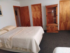 A room with a bed, a wooden wardrobe, and a cabinet.