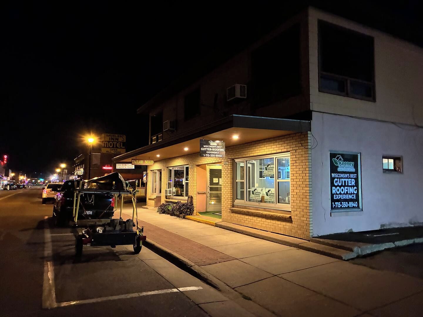 Ein Gebäude mit einem Schild für 'Wisconsin's Best Gutter Roofing Experience' und einer sichtbaren Ladeneinheit mit einem Schild 'Tailor Maid'.