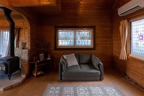 A cozy room with a fireplace, a sofa, and a window with stained glass.