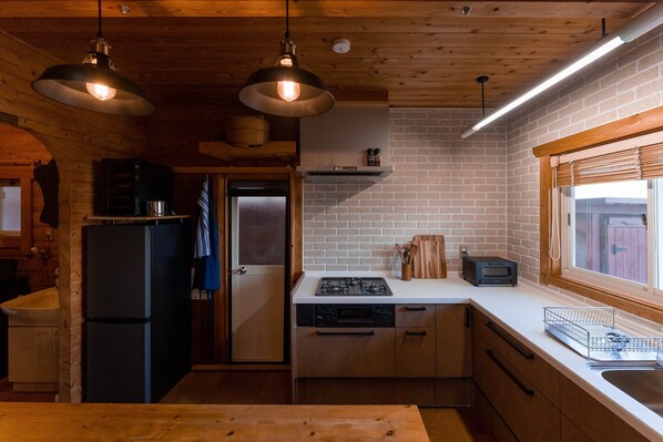 A compact kitchen with wooden cabinets, a built-in stove, and a window with blinds.