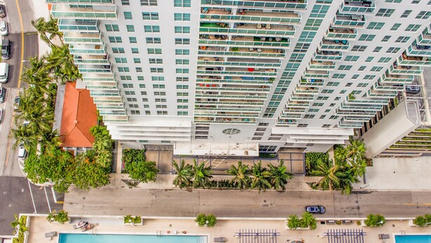 Un edificio alto con varios balcones, piscina y palmeras.