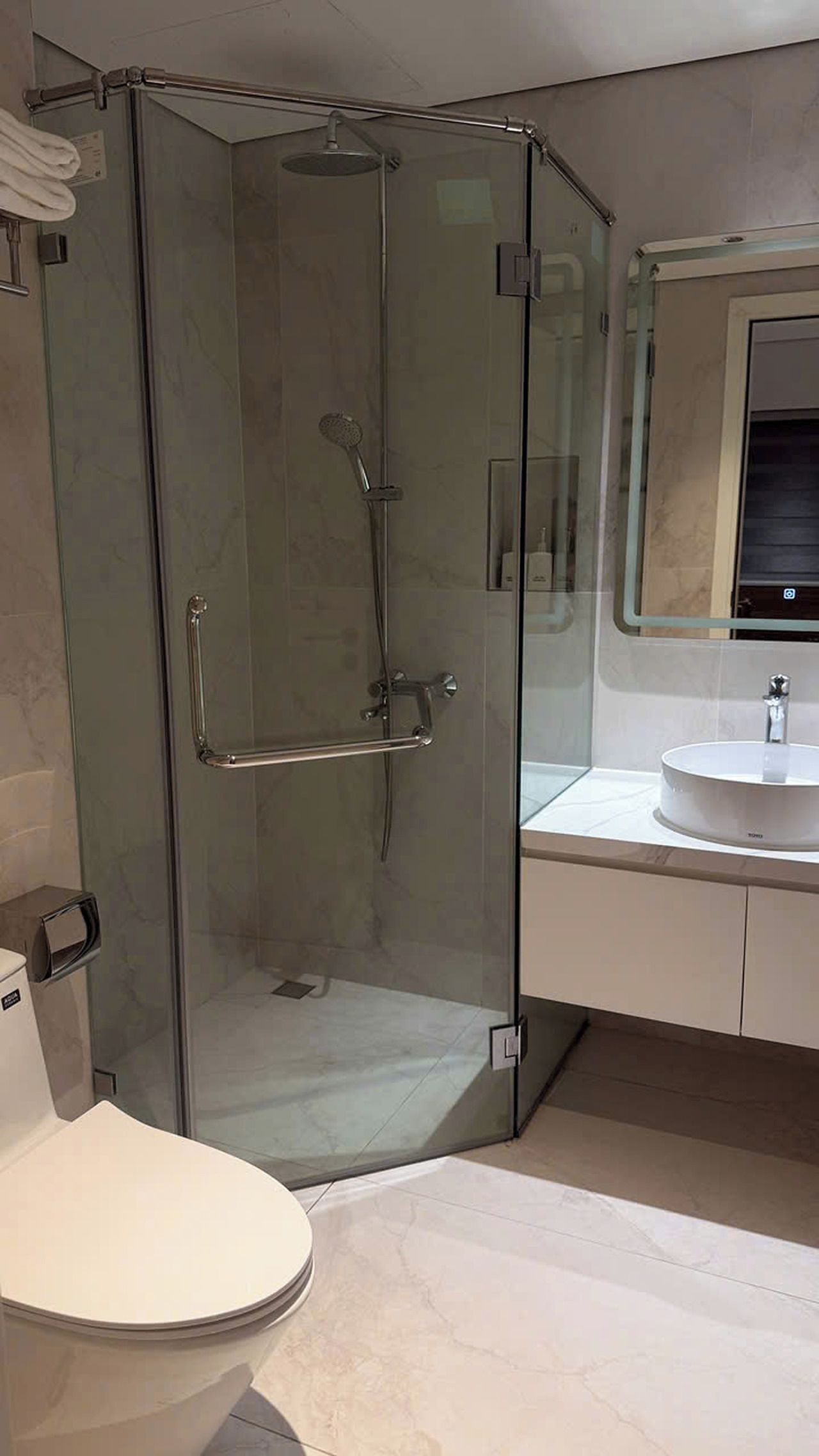 Ein modernes Badezimmer mit einer Duschkabine aus Glas, einer weißen Toilette und einem Waschbecken mit Spiegel.