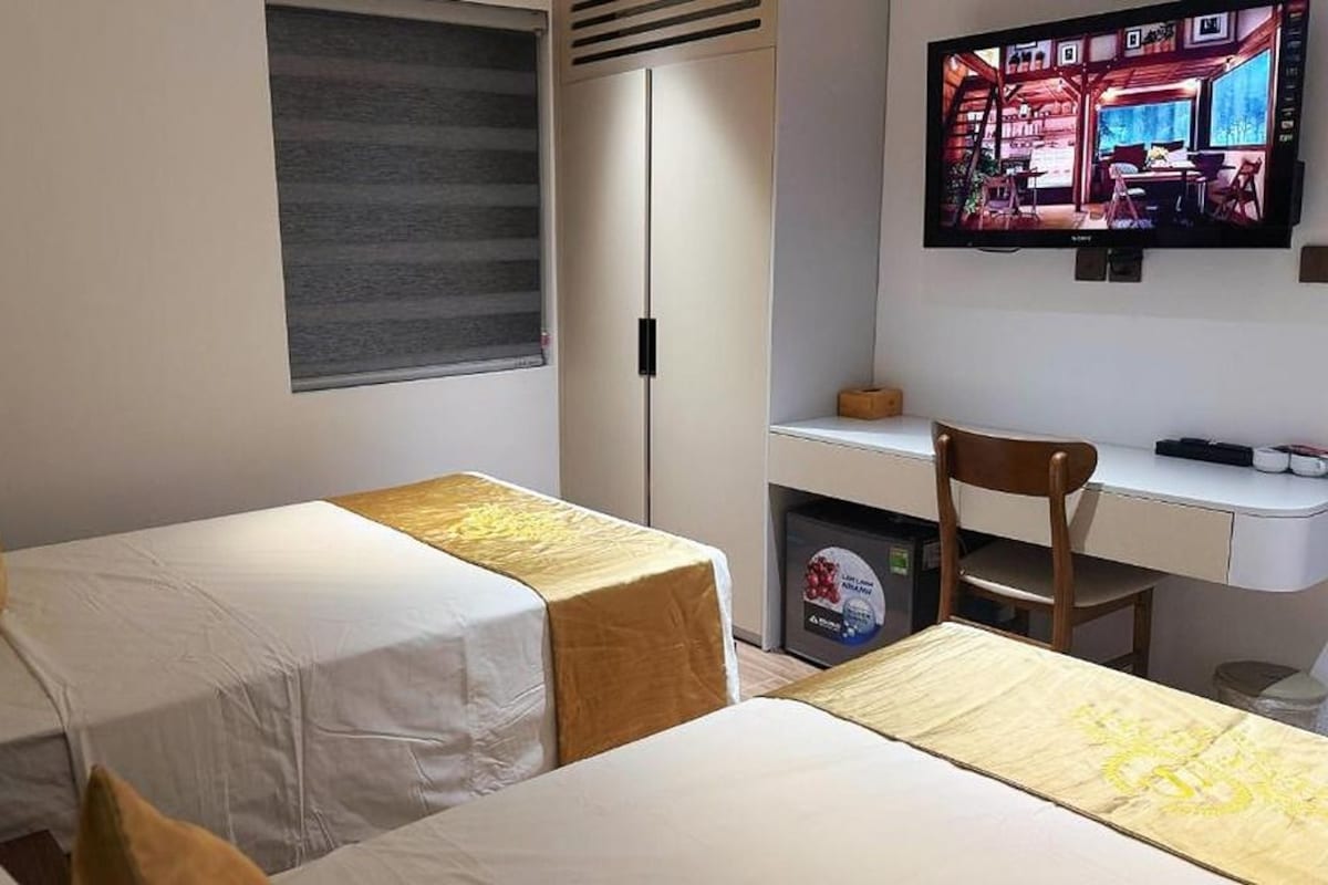 Habitación de hotel con dos camas, un escritorio, un televisor y un armario.