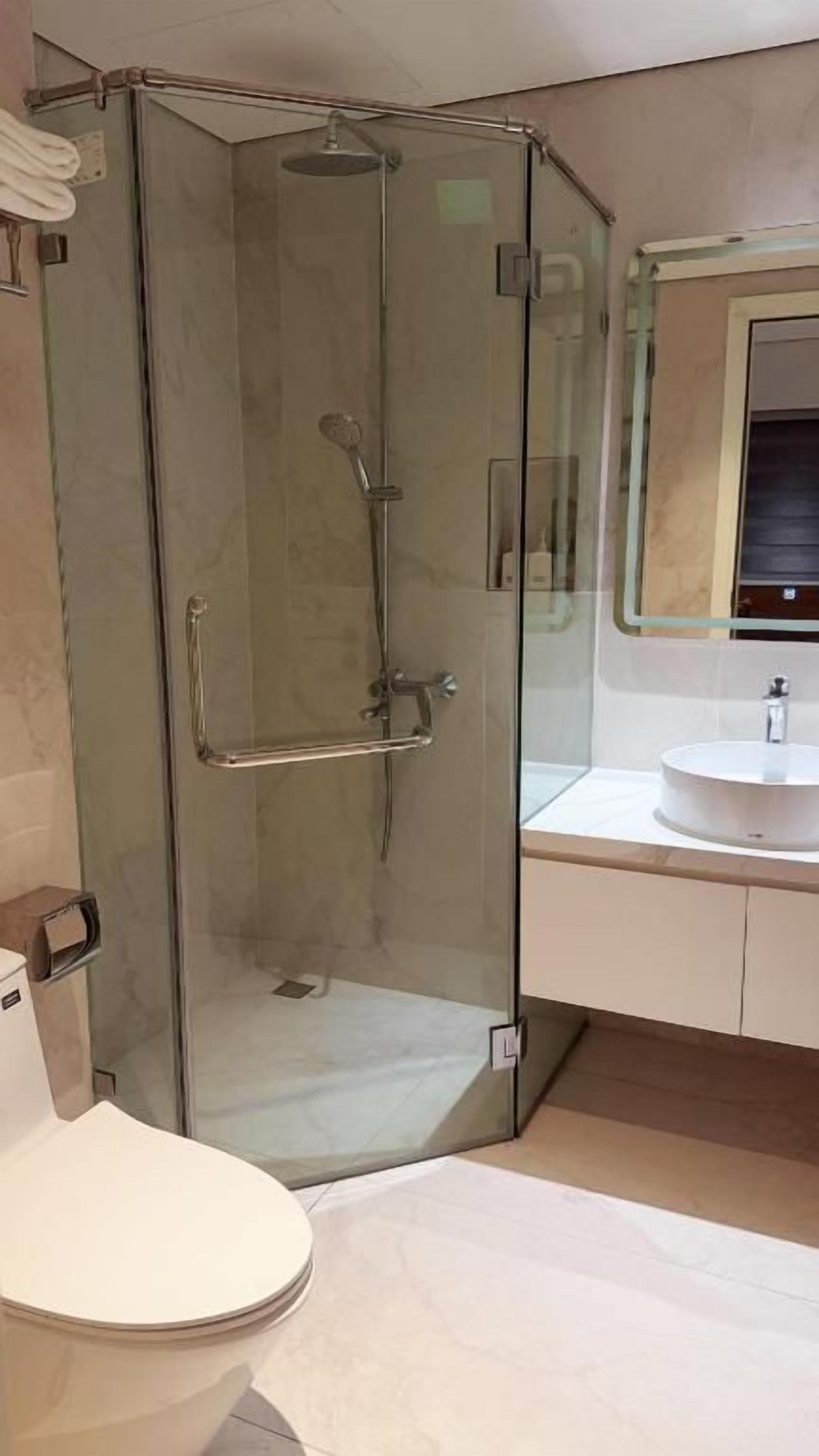 Un bagno con doccia vetrata, un water e un lavabo con specchio sopra.