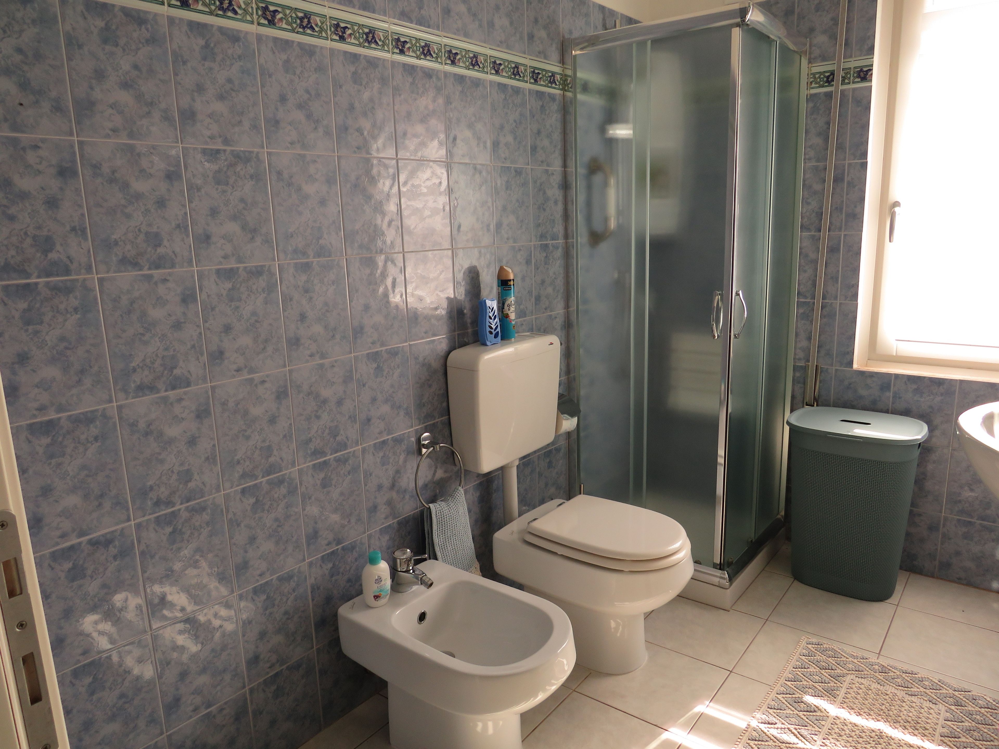 Une salle de bain équipée d’une douche, de toilettes, d’un bidet et d’une poubelle.
