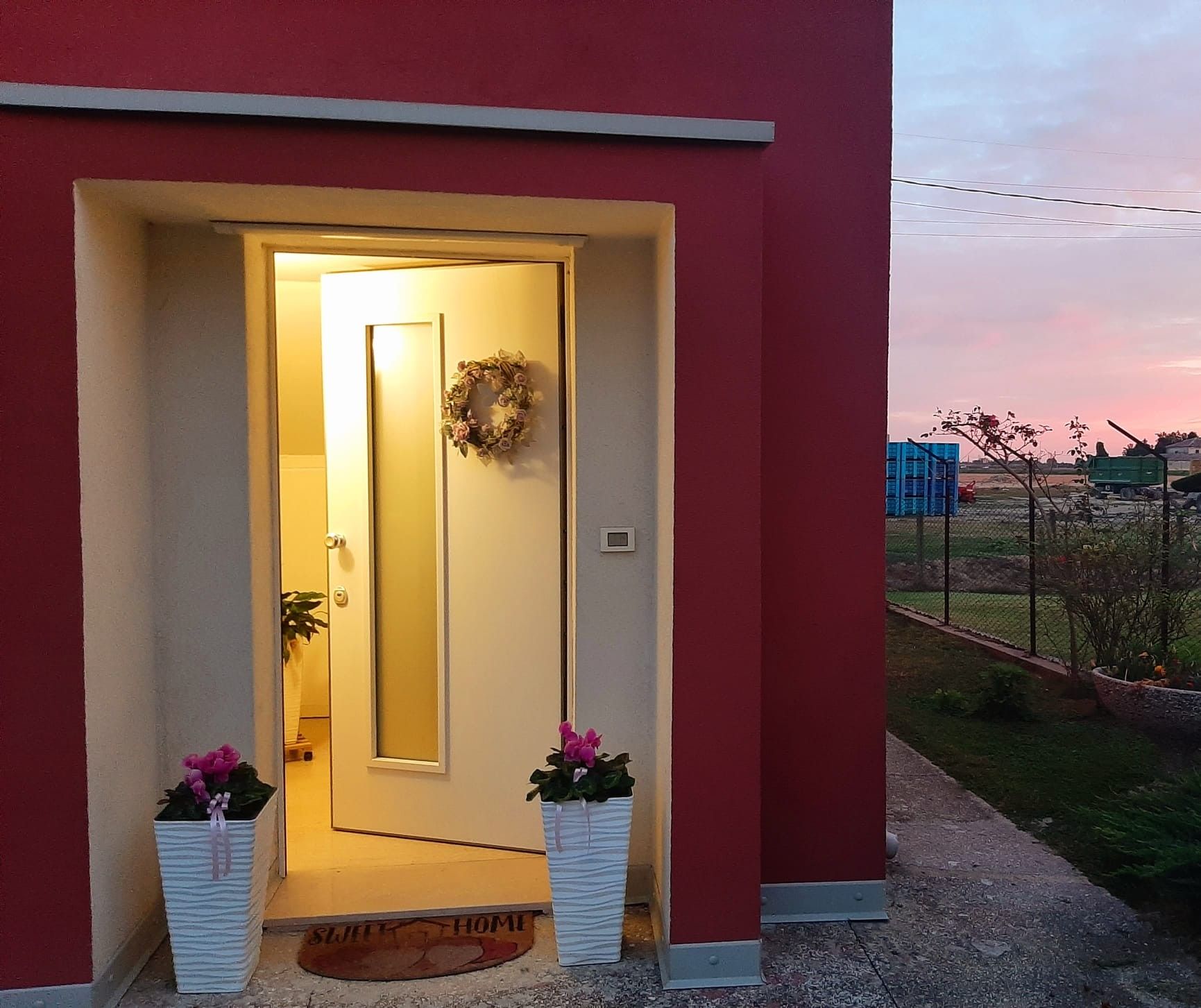 Una entrada de casa con una puerta, un adorno de Navidad y dos macetas.