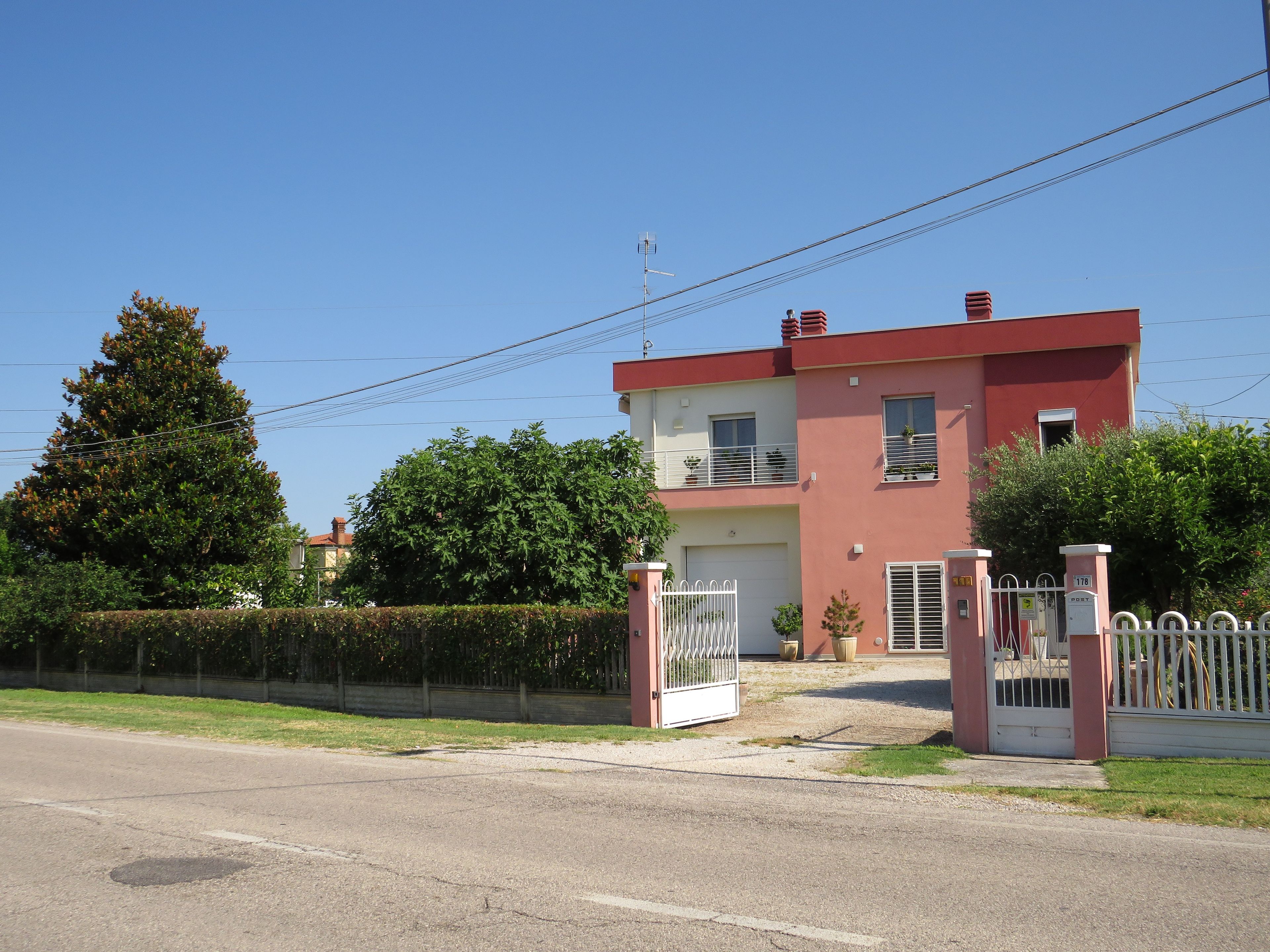 A two-story residential building with a gated entrance, a visible garage, and a clear sky.