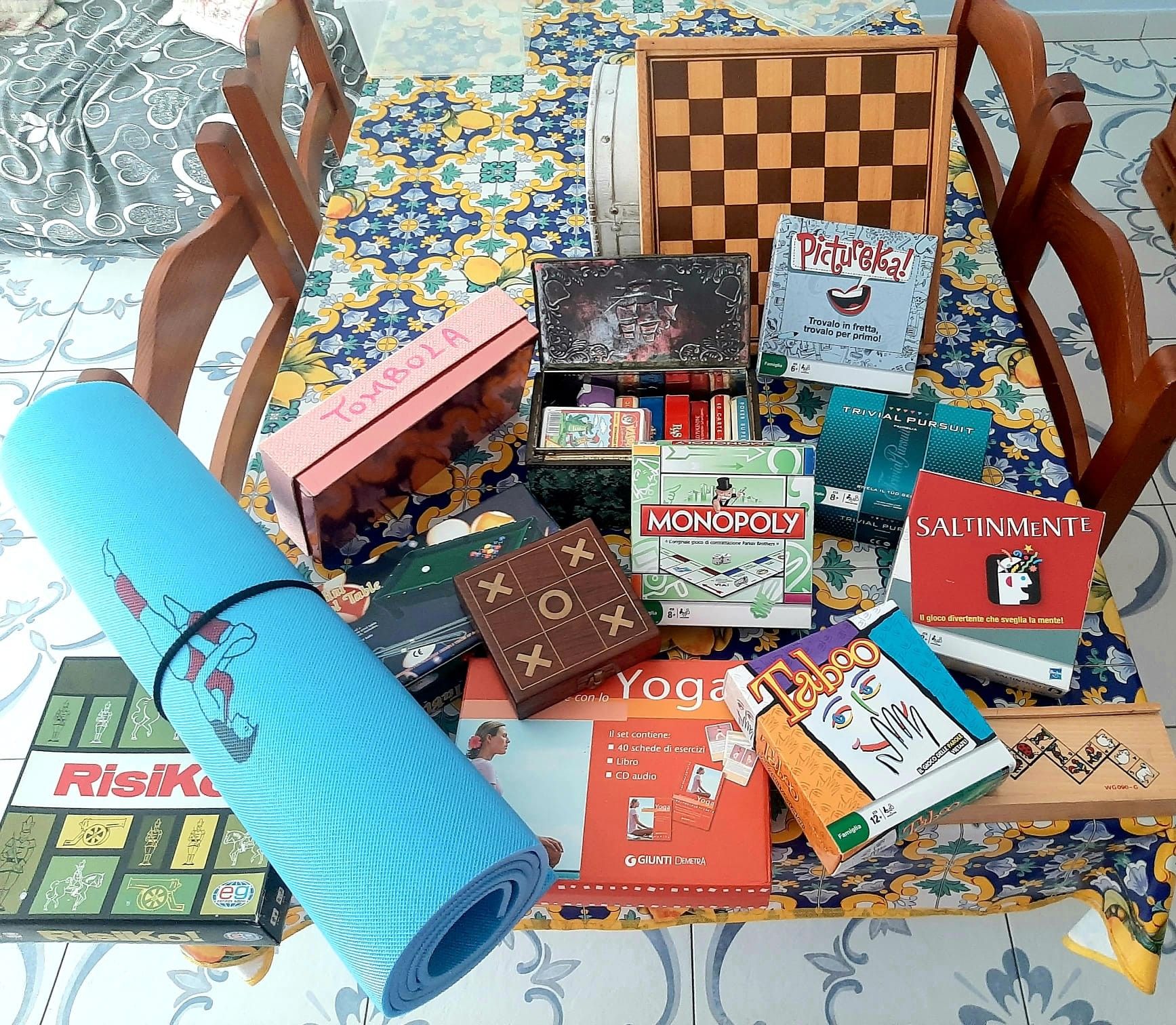Une variété de jeux de société et un tapis de yoga sur une nappe à motifs.