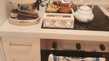 A kitchen with a coffee maker, a basket of snacks, a teapot, and a box of Bonomelli wine.