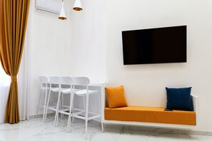 A modern room with a white sofa, a TV mounted on the wall, and a set of white chairs. - SUN SUITE - LUXURY APARTMENT IN THE CENTER (Napoli)