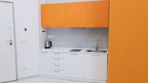 Une cuisine de taille réduite avec des meubles blancs, un évier et une machine à café.