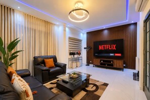 Una sala de estar moderna con un sofá de cuero, una mesa de centro y un televisor de pantalla plana mostrando el logotipo de Netflix.