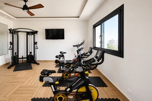 Een sportschool met trainingsapparatuur, een plafondventilator en een groot raam.
