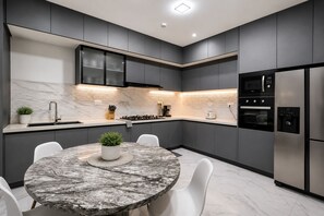 A modern kitchen with dark cabinetry, a marble countertop, and stainless steel appliances. - Spacious 3-bedroom apartment Dakar Fast Wifi with AC and gym, Centrally Located (Dakar)