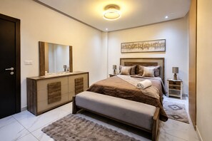 Un dormitorio moderno con una cama grande, mesitas de noche, un aparador y un espejo.