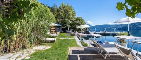 Propiedad frente al lago con muelle de madera, sillas de descanso y piscina.