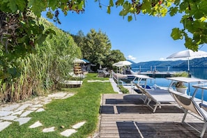 Propiedad frente al lago con muelle de madera, sillas de descanso y piscina.