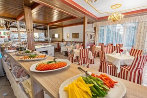 A restaurant with a buffet area, wooden ceiling, and striped chairs.