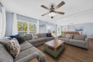 A spacious living room with a sectional sofa, a coffee table, and a ceiling fan. - The Great Escape (Gulf Shores)