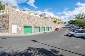 A street with stone buildings, green doors, and parked cars. - Charming 2-Bedroom Apartment with Pool, Terrace, and Air Conditioning (Las Palmas)
