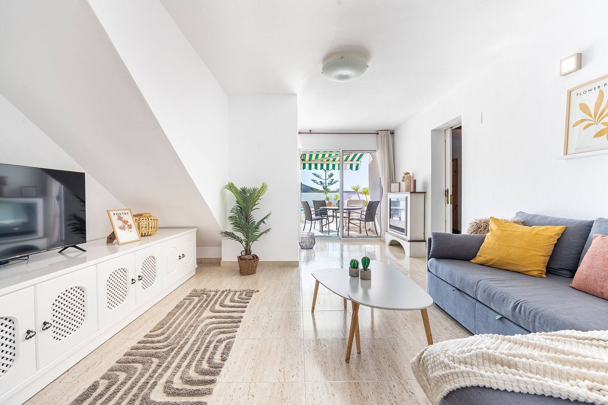 Un salon moderne avec un téléviseur, un canapé et une table basse.