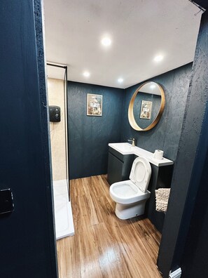 Casa de banho com design moderno, incluindo sanita, lavatório e espelho.