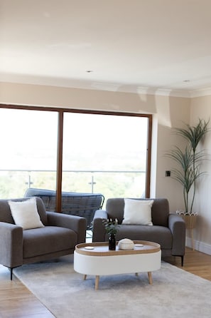 A modern living room with two sofas, a coffee table, and a large window. - Preseli Heights Luxury Indoor Pool House with Cinema & Bar (Llanreath)