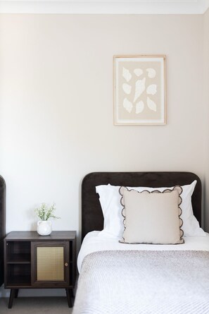 Ein Schlafzimmer mit einem Bett, einem Nachttisch und einem an der Wand hängenden Bild.