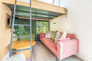 Ein modernes Interieur mit einem roten Sofa, einem Holztisch und einer Metallleiter.
