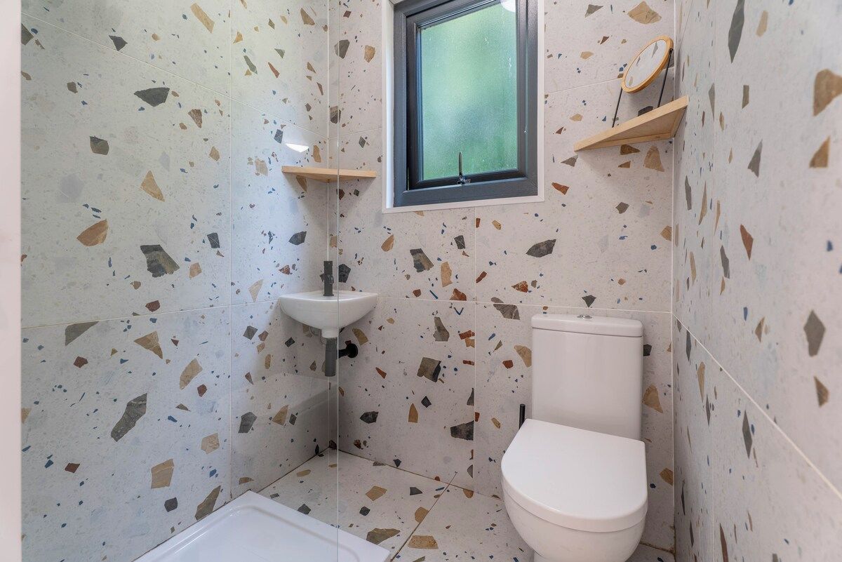 A small bathroom with a white toilet, a sink, and a window.