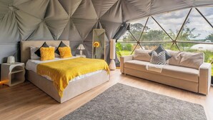 Ein modernes Schlafzimmer mit einem großen Bett, einer Couch und Blick ins Freie.