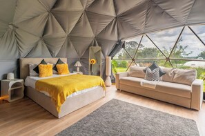 Ein modernes Schlafzimmer mit einem großen Bett, einer Couch und Blick ins Freie.