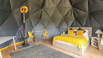 A modern bedroom with a tufted headboard, a bed with a yellow blanket, a desk, a chair, and a floor lamp.