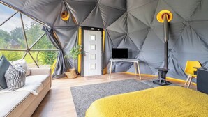 Eine Zelthotelunterkunft mit Bett, Sitzecke und Fernseher.