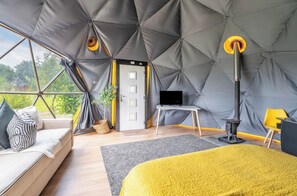 Eine Zelthotelunterkunft mit Bett, Sitzecke und Fernseher.