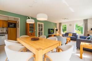 A modern living space with a dining area, kitchen, and seating area. - Charming Villa With Enclosed Garden (De Koog)
