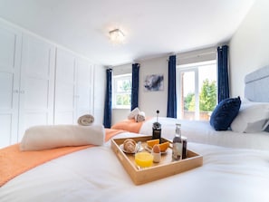 Habitación de hotel con cama, bandeja de desayuno y vistas a zonas verdes.