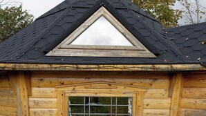 Una cabaña de madera con techo a dos aguas y una ventana con marco de madera.