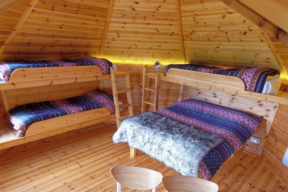A cozy, wooden interior with bunk beds and a ladder, suggesting a compact lodging space.