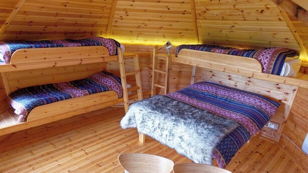 Un interior acogedor de madera con literas y una escalera, que sugiere un alojamiento pequeño.