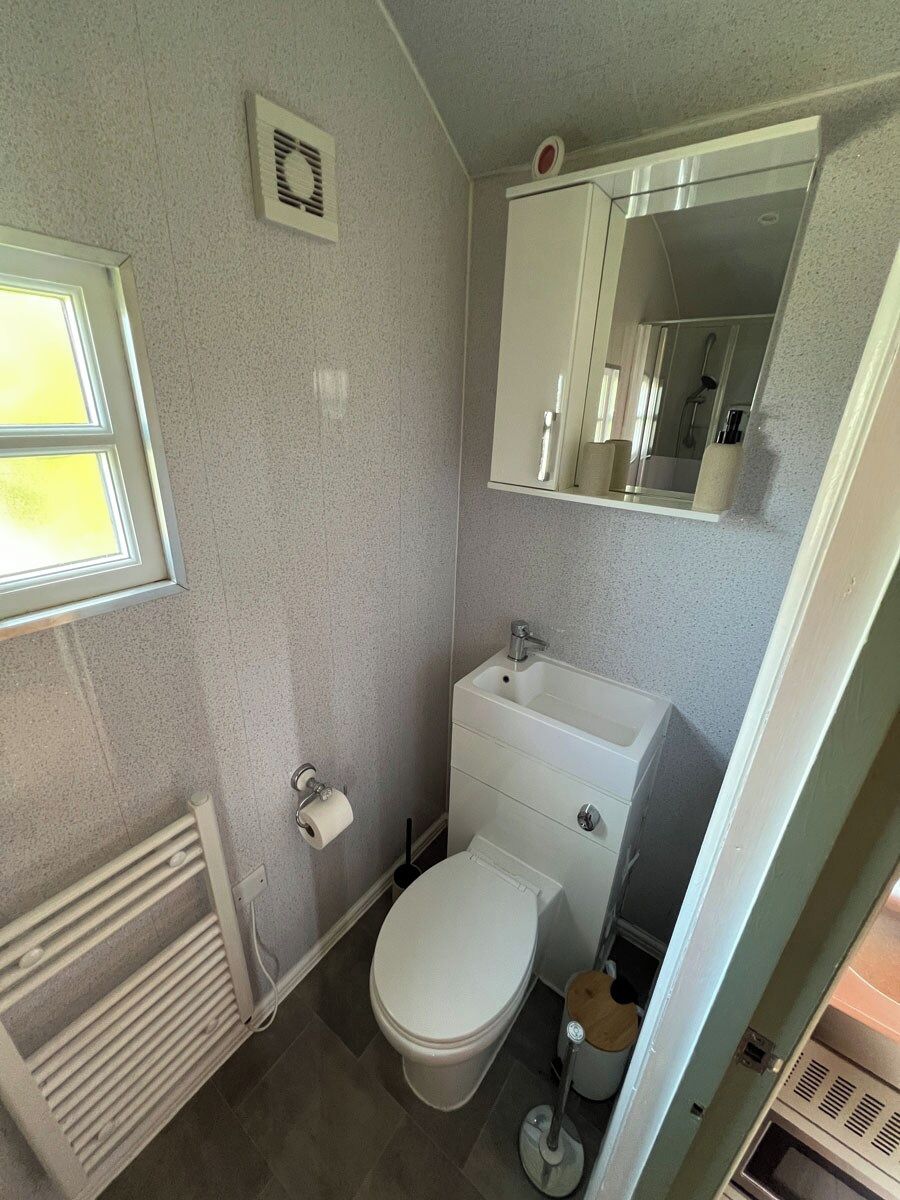 Pieni kylpyhuone, jossa on wc, pesuallas ja peili.