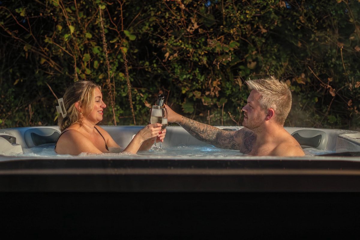 Dos personas en un jacuzzi rodeado de follaje.